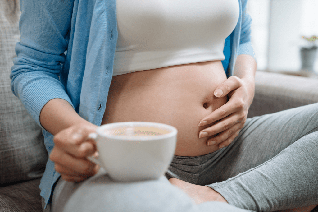 šálek kávy a těhotná žena