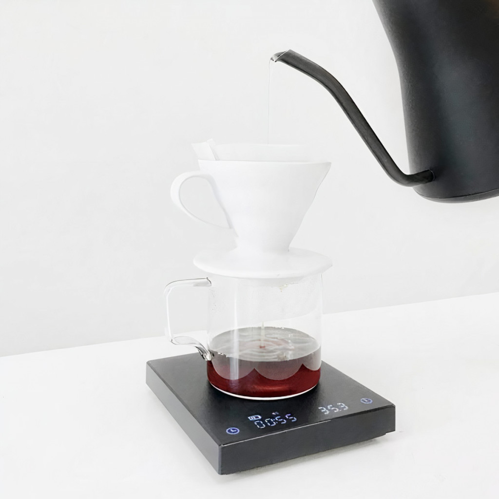černá baristická váha Timemore Black Mirror Basic během přípravy filtrované kávy pomocí bílého dripperu Hario V60