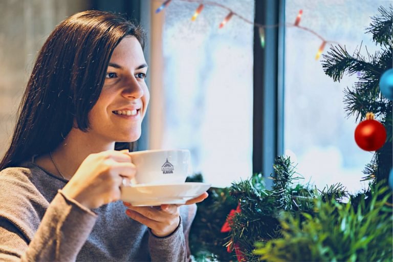 žena pije kávu u vánočního stromku